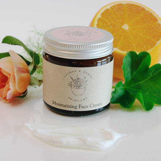 Amber glass jar with moisturiser and a rose and orange and geranium leaf