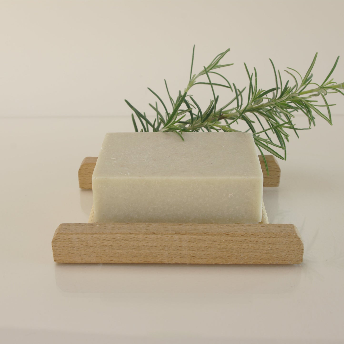 rosemary salt soap with rosemary leaves and on a bamboo soap rack