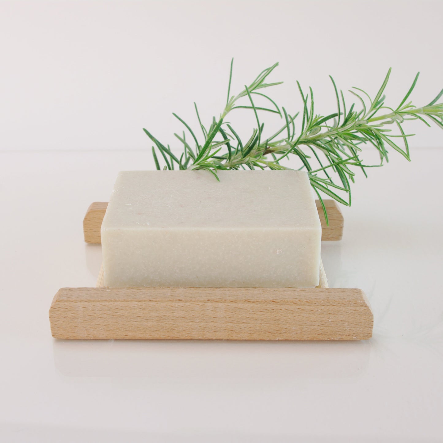 rosemary salt soap on a wooden soap rack with rosemary twig
