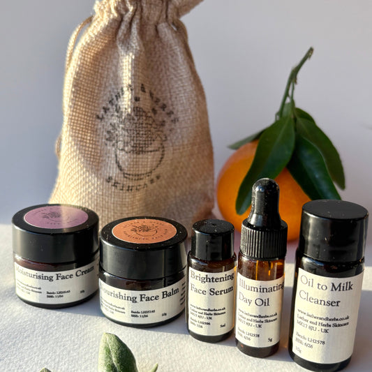 Collection of skincare products including jars and bottles with a burlap bag and oranges in the background.