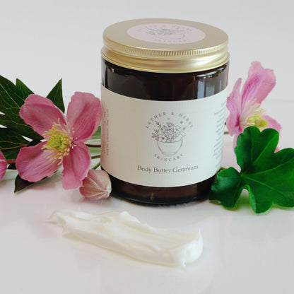 Jar of body butter with flowers and cotton swabs on a white background