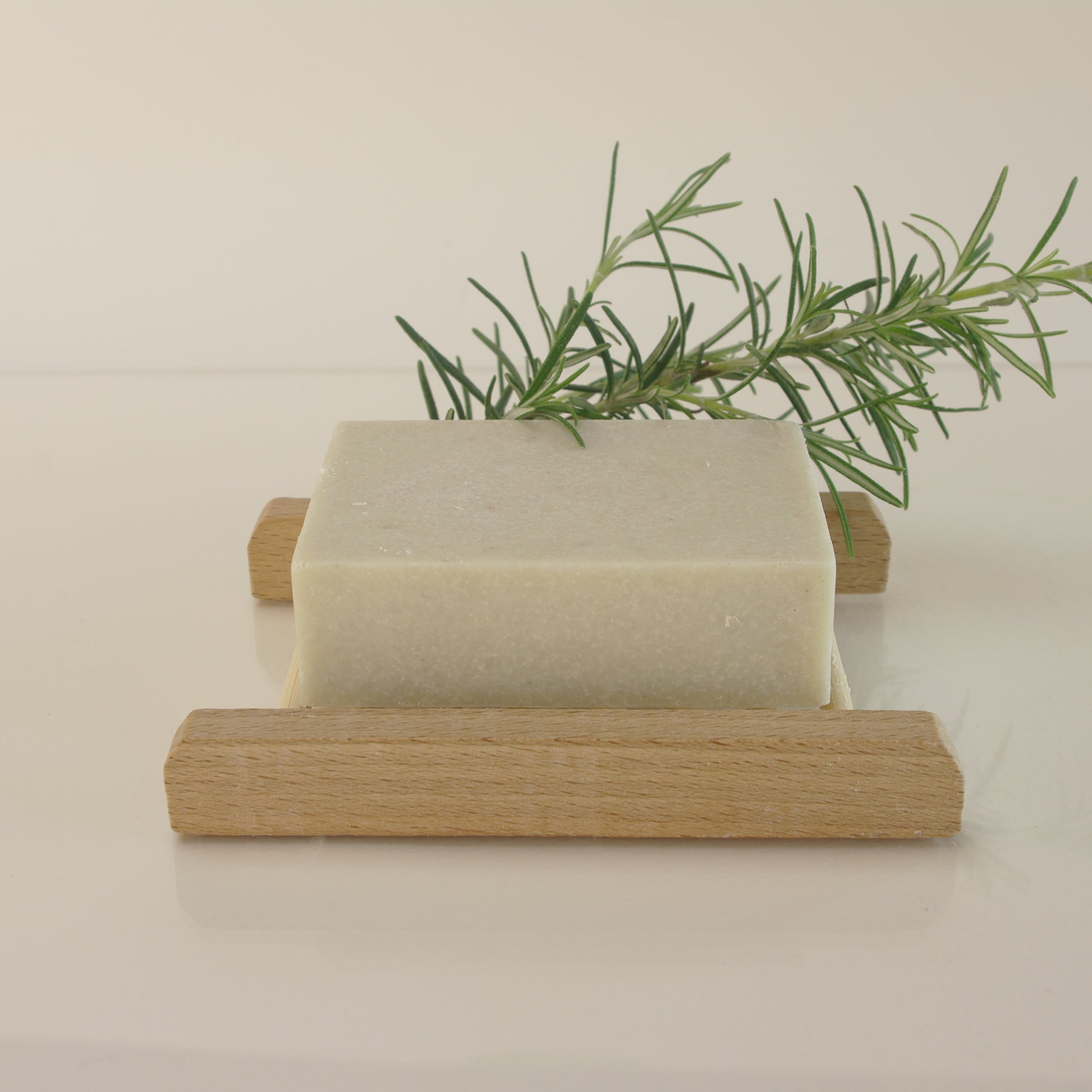 rosemary salt soap with rosemary leaves and on a bamboo soap rack