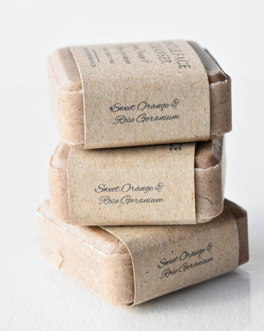 sweet orange and rose geranium gentle cleansing face wash bar a soft specked brown bar with  brown kraft recycled paper wrapband packaging