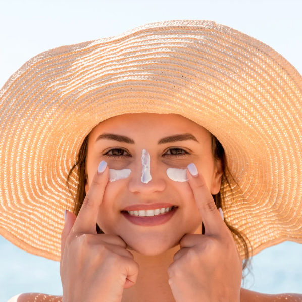 lady with sunhat an suncream on her face